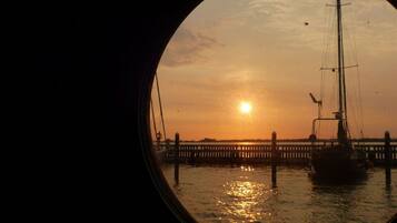 A sunset over a body of water with a pier and a sailboat.