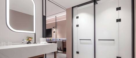 Un baño moderno con un espejo grande, un lavamanos y un perchero. Hay una puerta corredera con paneles de vidrio esmerilado y un marco negro.