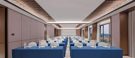 A conference room with rows of tables, each with a blue tablecloth, water bottles, and nameplates.