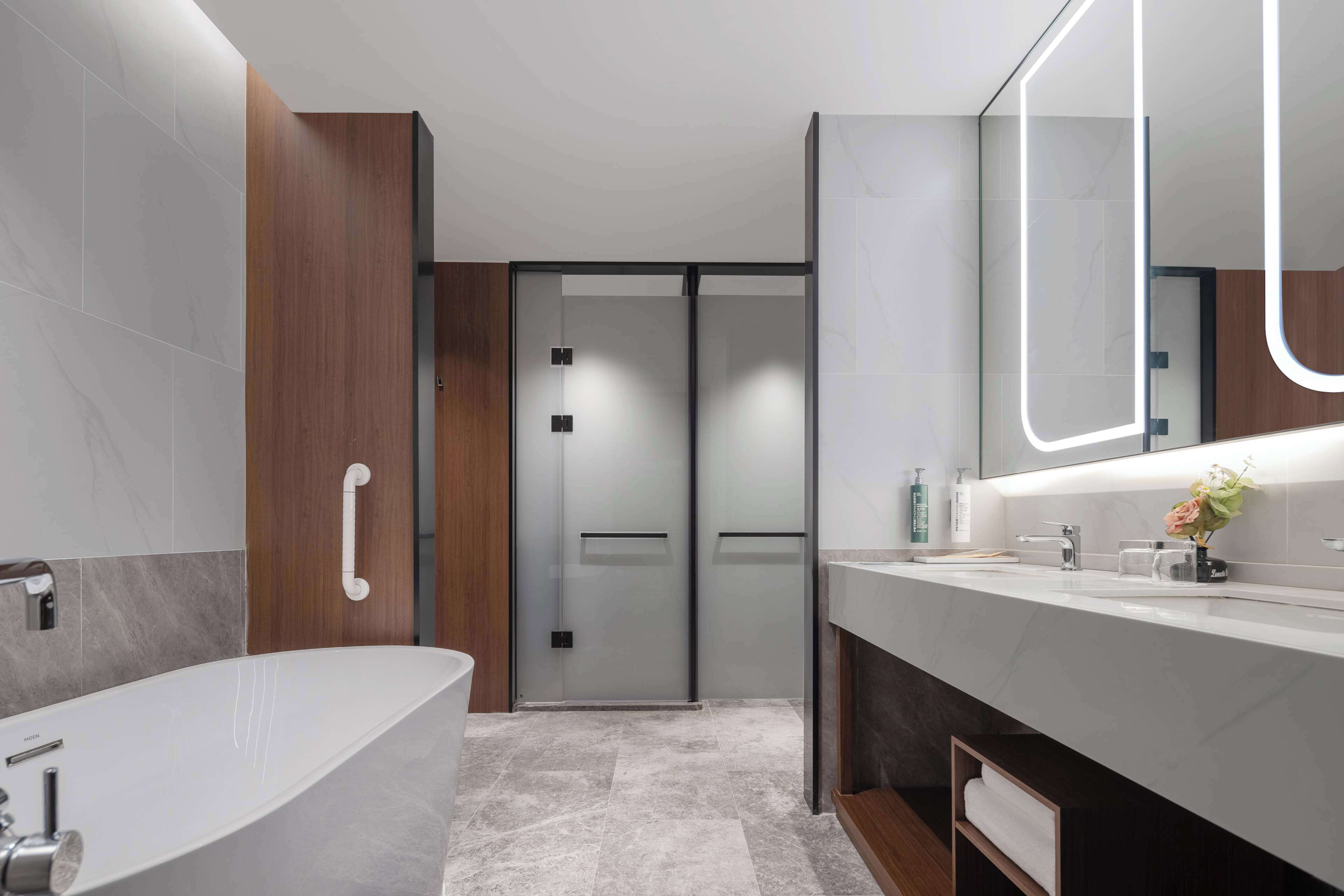 Un baño moderno con una bañera independiente, un tocador con espejo y una zona de ducha con puertas de cristal satinado.