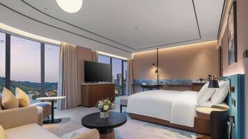 Habitación de hotel moderna con una cama grande, un sofá, un televisor y vistas a la ciudad.