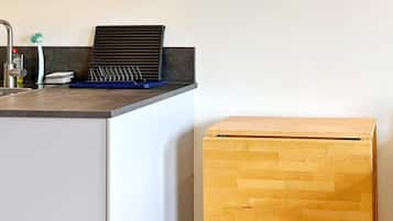 Una cocina con una laptop sobre la encimera, un fregadero y un armario de madera.