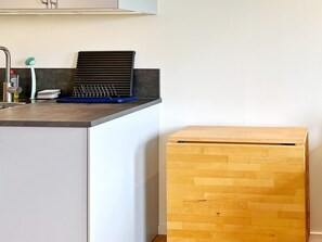 A kitchen with a laptop on the counter, a sink, and a wooden cabinet.