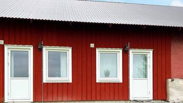 A red barn with four white-framed windows and a metal roof.
