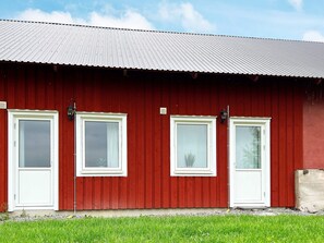 A red barn with four white-framed windows and a metal roof. - 5 Person Holiday Home in Munso (Munsö)