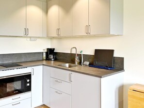 A modern kitchen with white cabinets, a Bosch oven, a coffee maker, and a sink with a faucet.