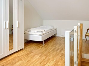 A bedroom with a single bed, wooden flooring, and a white wardrobe. - 5 Person Holiday Home in Munso (Munsö)