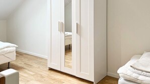 A room with a white wardrobe, a bed with white bedding, and a wooden floor. - 5 Person Holiday Home in Munso (Munsö)