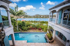 A pool with dolphins, a view of boats, and a mountainous landscape. - Villa Romance Free Concierge services (Cruz Bay)