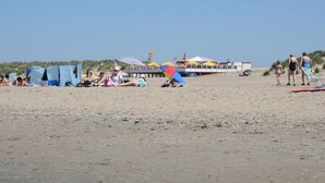 Una playa con tiendas de campaña y un muelle.