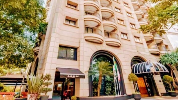 A tall, beige building with multiple balconies and a large entrance with a canopy. - HOTEL FARIA LIMA, LUXUOSO ALTO PADRÃO (São Paulo)