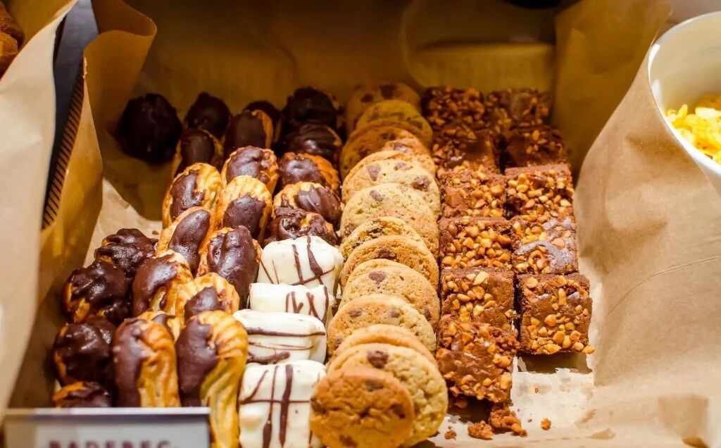 A variety of baked goods including chocolate-covered pastries, cookies, and nut-topped treats.