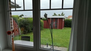 Une fenêtre donnant sur un bâtiment rouge et une cour verdoyante.
