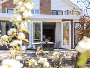 A modern two-story house with a patio area featuring a table and chairs. - Nature House With two Bedrooms and two Bathrooms (Kortgene)