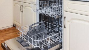 A kitchen with white cabinets, a dishwasher, and a countertop with a sink. - Holiday Home Weisse Robbe (Esens)