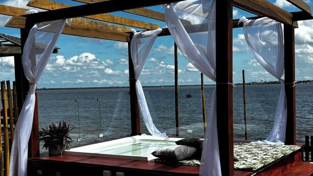A wooden deck with a bed and a view of the sea. - Chale das Torres (Belém)