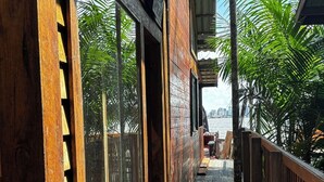 A wooden deck with large sliding glass doors leading to a covered outdoor area. - Chale das Torres (Belém)