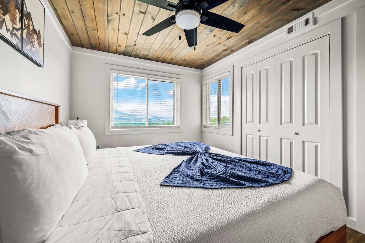 Ein Schlafzimmer mit Bett, Deckenventilator, Fenster und Tür.