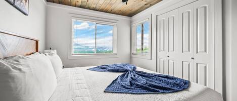 Un dormitorio con cama, ventilador de techo, ventana y puerta.