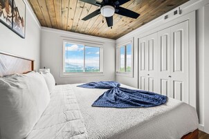 Quarto com uma cama, um ventilador de teto, uma janela e uma porta.