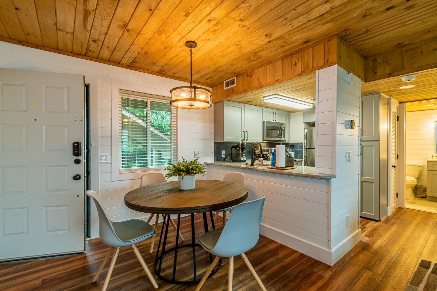 Una cocina moderna con armarios blancos, electrodomésticos de acero inoxidable y techo de madera.