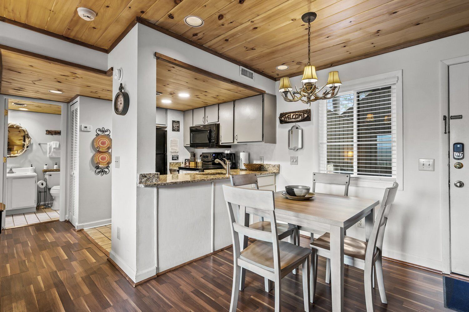 A modern kitchen with a central island, white cabinetry, and a chandelier.