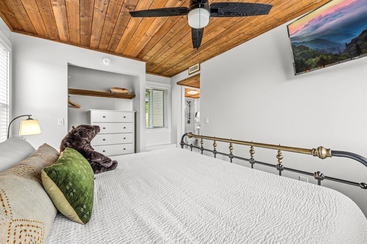 Ein Schlafzimmer mit Holzboden, einem Bett mit Metallkopfteil, einem Teddybären und einem Bild an der Wand.