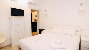 Habitació d'hotel amb llit, televisió, armari i escriptori.