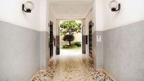 Un passadís amb un paviment de mosaic que condueix a una zona exterior amb un arbre.