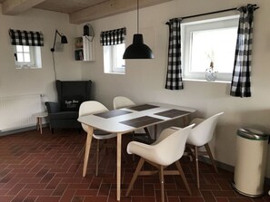 A dining area with a table, chairs, a black pendant lamp, and checkered curtains. - Hygge-huus-burhave Comfortable Holiday Residence (Butjadingen)