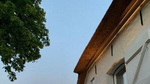 A white building with a stone facade, a wooden door, and a small window. - Hygge-huus-burhave Comfortable Holiday Residence (Butjadingen)