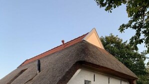 A white building with a thatched roof and a small window. - Hygge-huus-burhave Comfortable Holiday Residence (Butjadingen)
