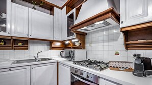Een moderne keuken met witte kasten, een gasfornuis, een ingebouwde oven en een koffiezetapparaat.