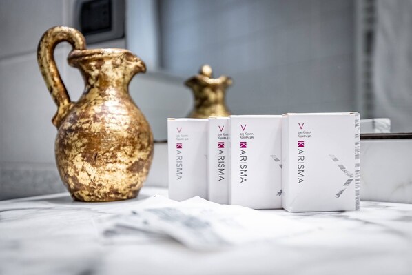A marble table with a golden pitcher and four white boxes with the brand 'Karisma'.