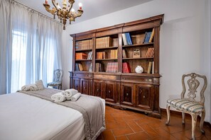 A bedroom with a large bed, a wooden bookcase, a chandelier, and a vintage chair. - YiD Elegant apt with garage (Firenze)