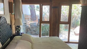 A bedroom with a large bed, wooden headboard, and a view of the outdoors through large windows. - Casa Vallesana, Fraccionamiento "El Coporito", Magnificent lake view (Valle de Bravo)
