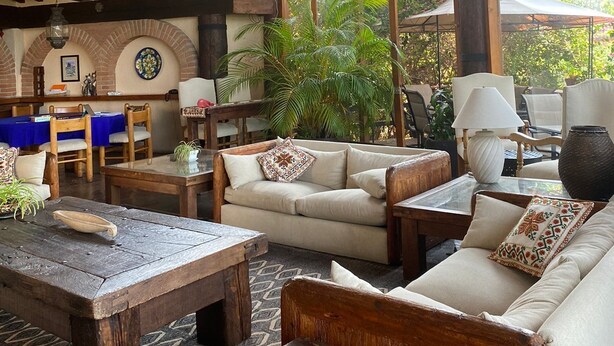 A rustic interior with wooden furniture, a dining area, and large windows overlooking greenery. - Casa Vallesana, Fraccionamiento "El Coporito", Magnificent lake view (Valle de Bravo)