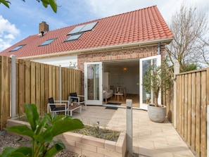 A house with a red-tiled roof, a brick exterior, and a wooden fence. - Charming Holiday Home With a Terrace (Zoutelande)