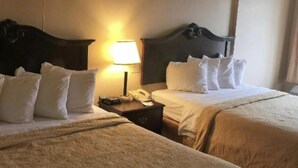 Una habitación de hotel con dos camas, una lámpara de noche, un teléfono y una mesita de noche.