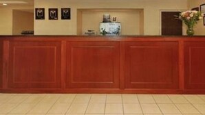 Un mostrador de recepción con detalles de madera, suelo de baldosas y cuadros enmarcados en la pared.