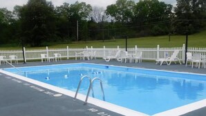 Una piscina con valla blanca y sillas de descanso alrededor.