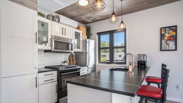 A modern kitchen with white cabinets, stainless steel appliances, and a black countertop island.