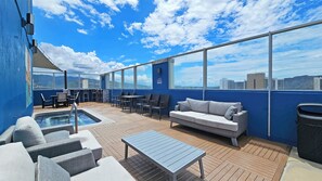 Une terrasse sur le toit avec une piscine, un espace salon et une vue sur la ville.