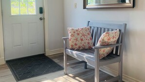 Une pièce avec un banc en bois, une porte dotée d’une fenêtre et un grand miroir accroché au mur.
