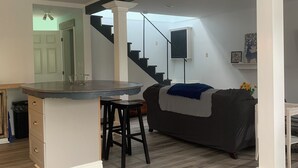 Une cuisine moderne dotée d’un îlot central, d’un coin repas avec une table ronde et d’un escalier menant à un niveau supérieur.