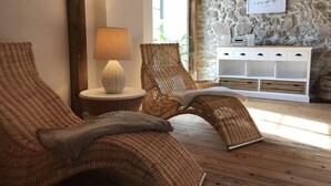 Ein Zimmer mit Korbmöbeln, einer Lampe, einer Steinwand und einem weißen Schrank.