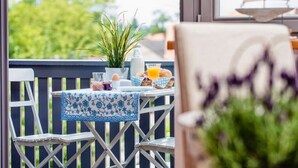 Ein Balkon mit einem Tisch, gedeckt für das Frühstück, darunter Brot, Eier und Saft.