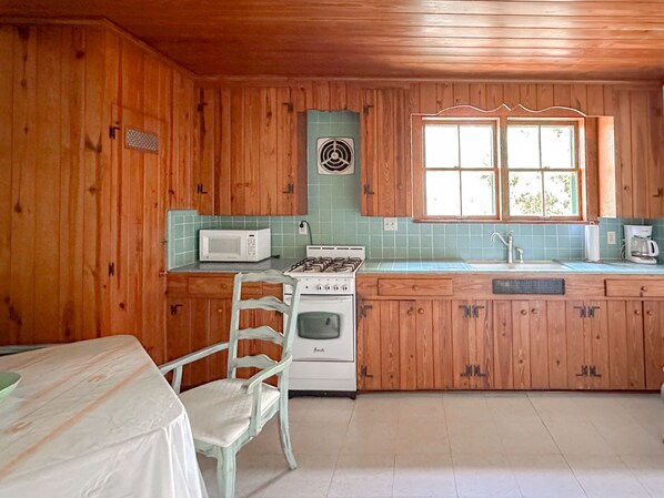 A kitchen with wooden cabinets, a microwave, a stove, and a sink. - Victorian Apt. w/ Tailgate Spot near Stadium! (Gainesville)