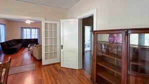 Een ruime woonkamer met een donkergrijze bank, een bijzettafeltje en een houten kast met glazen deuren.