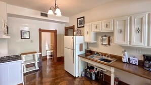 Una cocina con gabinetes blancos, un lavamanos doble, un refrigerador y una estufa.